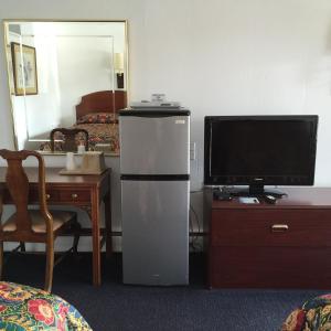a room with a refrigerator and a tv and a table at Valley Motel Pittsburgh in Harmarville