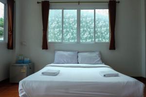 a bedroom with a large white bed with a window at Bai Pai Resort in Khlung