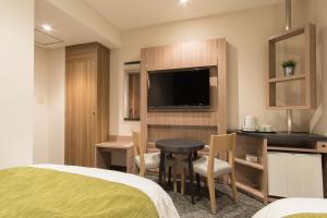 ein Hotelzimmer mit einem Bett, einem Tisch und einem TV in der Unterkunft Fujinomiya Fujikyu Hotel in Fujinomiya