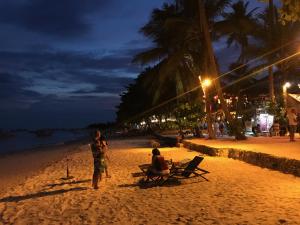 two people are sitting on a beach at night at Pyramid Resort in Panglao