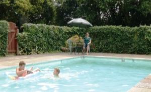 Tres niños nadando en una piscina con sombrilla en Glow Worm Motel en Waitomo Caves