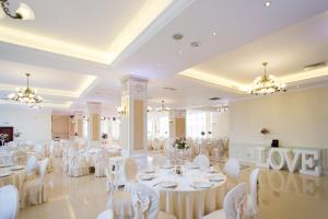 une salle de banquet avec des tables blanches et des chaises blanches dans l'établissement Hotel Capitol, à Iaşi