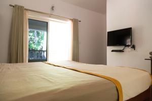 Un dormitorio con una cama grande con una ventana grande. en Hill Top Goa Lodge, en Vagator