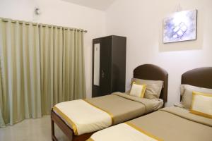 Habitación de hotel con 2 camas y cortinas en Hill Top Goa Lodge en Vagator