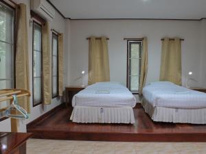 two beds sitting in a room with windows at Baan Maka Nature Lodge in Kaeng Krachan