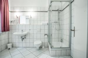 a bathroom with a shower and a toilet and a sink at Waldsee Hotel am Wirchensee in Treppeln