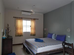 Schlafzimmer mit einem Bett mit blauer Bettwäsche und einem Fenster in der Unterkunft Khaolak Summer House Resort in Khao Lak