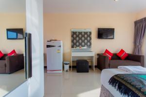 a living room with a couch and a refrigerator at Surin Sunset Hotel - SHA in Surin Beach