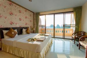 una camera con un grande letto e una grande finestra di Surin Sunset Hotel - SHA a Surin Beach Altre 37 foto