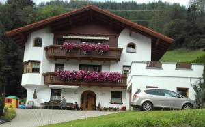 a white house with a balcony with purple flowers at Apartment Maierhof in Flirsch