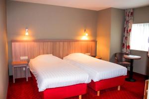 two beds in a hotel room with red carpet at La Couronne in Welkenraedt