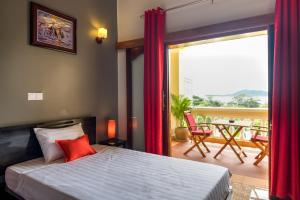 a bedroom with a bed and a balcony with a table at Riviera Hotel & Resort Kep in Kep