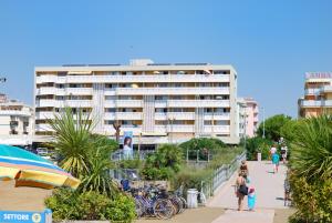 ビビオーネにあるCondominio Skorpiosの歩道を歩く人々のいる浜辺の建物