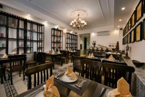 a restaurant with tables and chairs and a chandelier at Hanoi Center Silk Premium Hotel & Spa & Travel in Hanoi