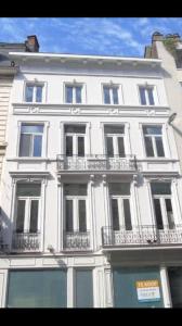 een groot wit gebouw met balkons in een stadsstraat bij Your suite Ghent in Gent
