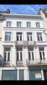 a large white building with balconies on a city street at Your suite Ghent in Ghent