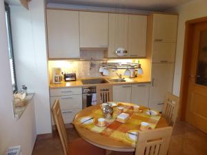 uma cozinha com uma mesa de madeira e uma cozinha com armários brancos em Ferienwohnung Villa Laura em Kühlungsborn