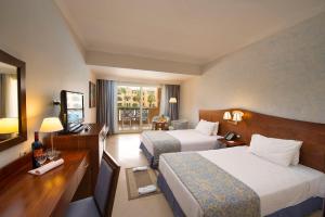 een hotelkamer met 2 bedden en een televisie bij Stella Gardens Resort & Spa, Makadi Bay in Hurghada