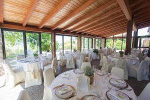 un salón de banquetes con mesas y sillas blancas y ventanas en Palazzo Loup Hotel, en Loiano
