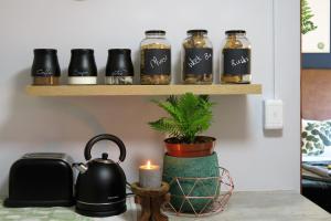 a shelf with jars of spices and a candle at Pillow & Fern in George