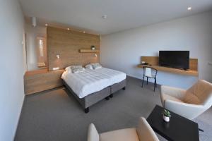 a bedroom with a bed and a tv and a couch at Hotel Berghoeve in Epen