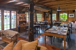 a dining room with tables and chairs and windows at Hotel El Barranco in Futaleufú