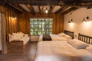 1 dormitorio con 3 camas y ventana en Hotel El Barranco, en Futaleufú