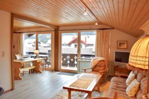 ein Wohnzimmer mit einem großen Fenster und einem Schreibtisch in der Unterkunft FeWo Lebensfreude in Mittenwald
