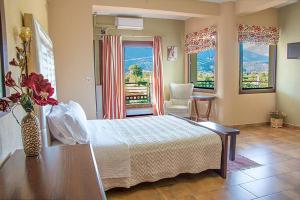 a bedroom with a bed and a table and windows at Gea Kaimaktsalan Hotel & Spa in Kato Loutraki