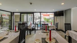 a restaurant with white tables and chairs and windows at Aroma Angkor Boutique Hotel in Siem Reap