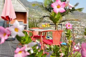 a table and chairs on a balcony with pink flowers at Casa Horizonte in Arco da Calheta
