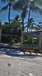 a gate at a resort with palm trees in the background at Casa da Maisa in Porto Seguro