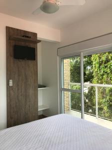 1 dormitorio con cama y ventana grande en Bombinhas Quinta do Mar Complexo B, en Bombinhas