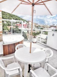 una mesa blanca y sillas con sombrilla en el balcón en Bombinhas Quinta do Mar Complexo B, en Bombinhas