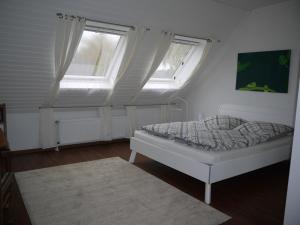 a small bedroom with a bed and two windows at fewo-wachtendonk in Wachtendonk