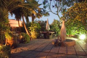 a patio with a table and an umbrella and trees at La Bodega Casa Rural, Tenerife. in San Miguel de Abona