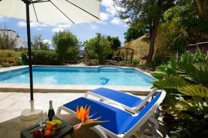 a swimming pool with a blue chair and an umbrella at La Bodega Casa Rural, Tenerife. in San Miguel de Abona