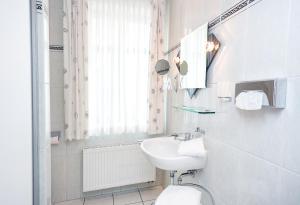 
a bathroom with a sink, toilet and mirror at Hotel Stadt Waren in Waren
