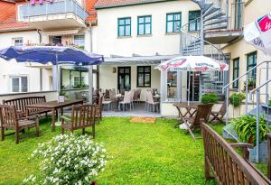 a patio with tables and chairs and umbrellas at Hotel Stadt Waren in Waren