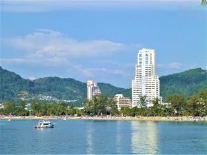 a boat in the water in front of a city at Patong Tower Amazing Sea View 12 by PHR in Patong Beach