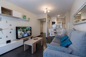 ein Wohnzimmer mit einem blauen Sofa und einem TV in der Unterkunft Apartamento Playa Mar Portonovo Centro. in Sanxenxo