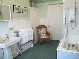y baño con lavamanos, ducha y silla. en Hollybank House en Emsworth