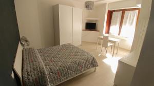 um quarto com uma cama, uma mesa e uma janela em Casa Roncalli em Foligno