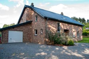 a brick house with a garage in front of it at Gite L'Armandier in Sart-lez-Spa