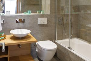 a bathroom with a toilet and a sink and a shower at Hotel Crown in Andermatt