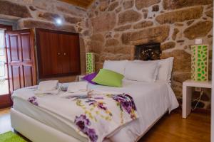 1 dormitorio con 1 cama grande en una pared de piedra en Casa Rautau, en Soajo