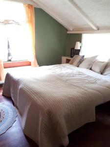 a large white bed in a bedroom with a window at Voorhuis in Eelde-Paterswolde