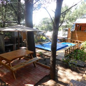 una mesa de picnic con una sombrilla junto a una piscina en Cabanas Las Escondidas, en Monte Hermoso