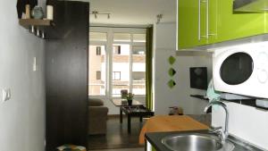 cocina con armarios verdes y sala de estar. en Apartamento Rulosol 1, en Torremolinos