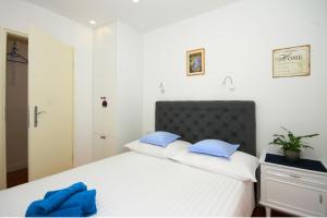 een slaapkamer met een wit bed met blauwe kussens bij Apartment Zorica in Omiš
